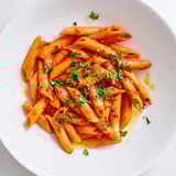 Close-up of vibrant penne all'arrabbiata, garlic and chili flakes permeating the spicy tomato sauce.