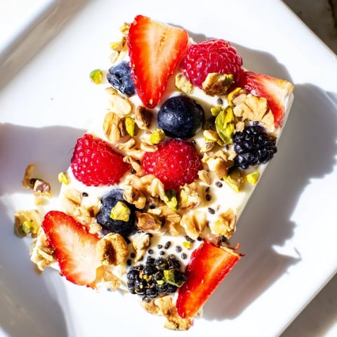 Vibrant frozen fruit yogurt bark with colorful berries and crunchy granola, a tasty treat.