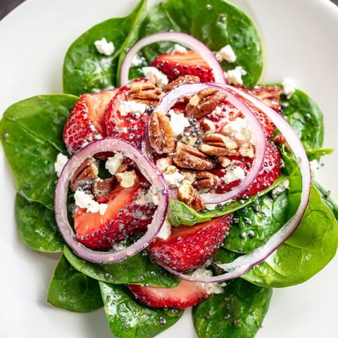 Fresh spinach strawberry salad bursting with color, topped with pecans, ready to enjoy.