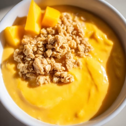 Smooth, creamy Mango Blended Overnight Oats, topped with crunchy granola and fresh mango slices for breakfast.