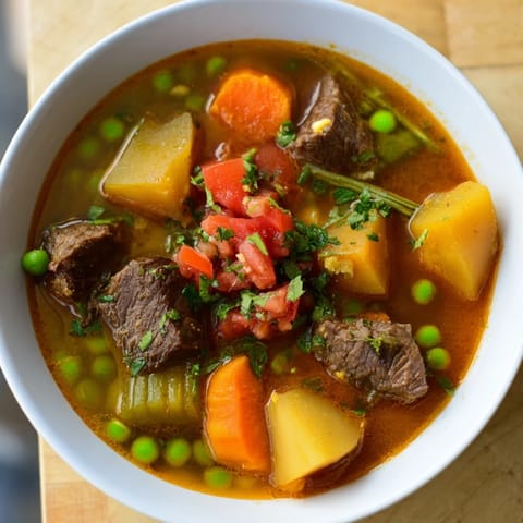 A close-up of a rich, bubbling One-Pot Hearty Beef and Barley Soup with chunks of beef and vegetables.