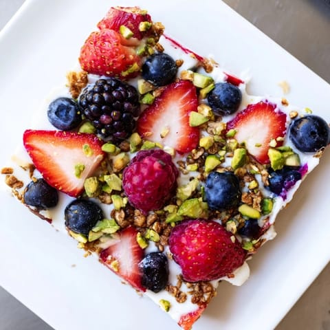 Close-up of frozen fruit yogurt bark with a swirl of purple berries, ready to break and eat.