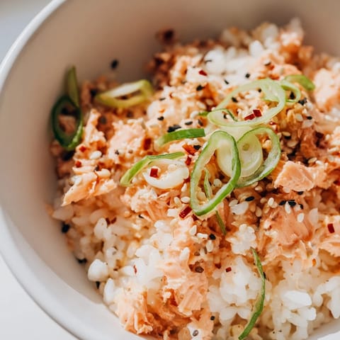 Golden rice and pink salmon flakes mix with vibrant green avocado and sesame seeds in this comforting Emily Mariko Salmon Rice Bowl, served alongside crispy nori sheets.