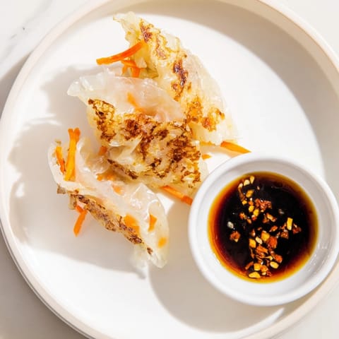 Golden-brown Crispy Rice Paper Dumplings on a plate, filled with seasoned ground chicken and vegetables, served with a small bowl of tangy dipping sauce.