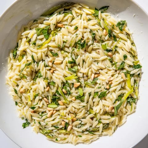This vibrant Asparagus Lemon Orzo Salad features bright lemon zest, crisp asparagus shavings, and toasted pine nuts on a bed of al dente orzo.