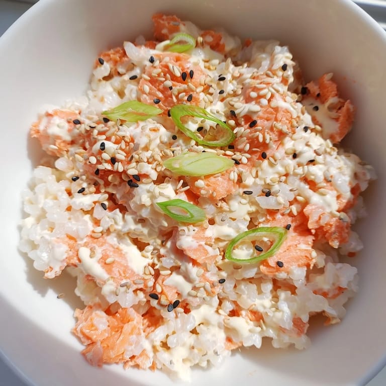 The viral Emily Mariko Salmon Rice Bowl is displayed in a cozy kitchen setting, ready to be scooped into fresh seaweed wraps for a delicious hand-roll experience.