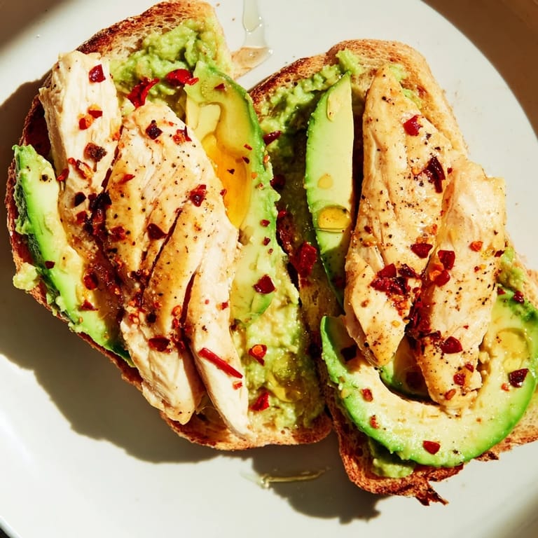 Savory-sweet Smashed Avocado Chicken Toast plated with juicy chicken, mashed avocado, chili flakes, and honey drizzle for brunch.
