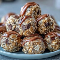 No-bake oat bites with peanut butter and chocolate chips in a clear glass bowl, ready for rolling into energy balls.