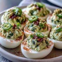 Guacamole Stuffed Deviled Eggs with creamy avocado filling, topped with smoked paprika and fresh cilantro for a vibrant appetizer.