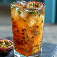 A vibrant tropical sunrise mocktail with passionfruit and orange juice, garnished with fresh mint and orange slices.  